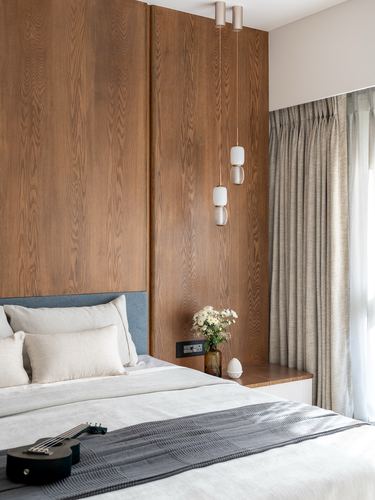 Bedroom with wood-paneled headboard wall, pendant lights, and neutral bedding