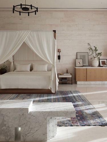 Minimalist bedroom with draped canopy bed, ribbed stone wall, and sculptural marble bench