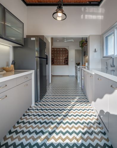 Galley kitchen with grey cabinetry and teal-beige chevron tile floor, pendant light overhead