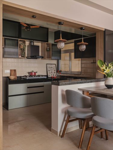 Kitchen with sage cabinetry, black granite counters, ribbed pendant lights, and grey bar stools at breakfast counter