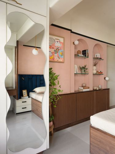 Bedroom with pink lime-plaster wall, arched niche shelving, wavy mirror, and fluted wood cabinetry