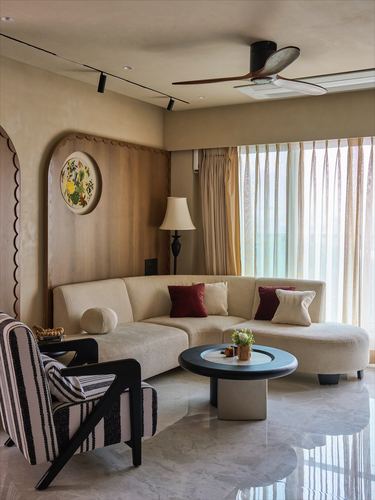 Living room with curved beige sectional, scalloped wood wall panel, and round black coffee table