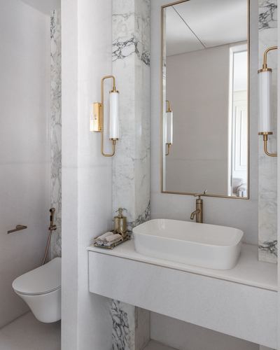 Marble bathroom with brass sconces, framed mirror, and a rectangular vessel sink