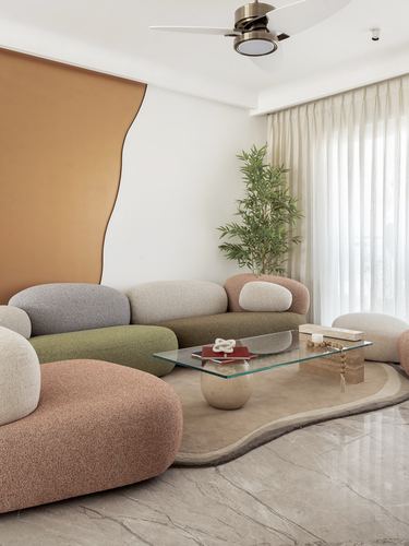 Curved boucle sofa in muted tones around a glass coffee table on a marble floor