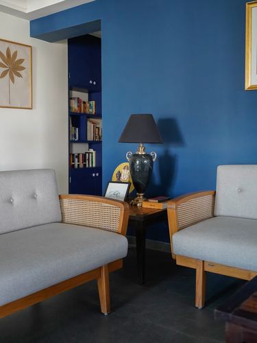 Two cane-backed armchairs flank a side table with a marble lamp against a deep blue wall niche