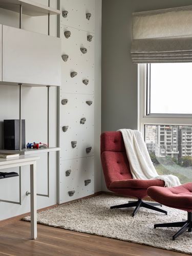 Study nook with climbing wall panel and red swivel lounge chair by window