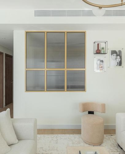 Living room with brass-framed fluted glass partition, beige sofas, and gallery wall