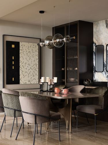 Dining room with marble table on brass base, globe pendant lights, dark cabinetry and stone accent wall