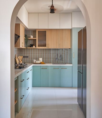 Mint green and wood kitchen viewed through a rounded archway with patterned backsplash