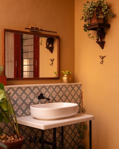 Ochre bathroom corner with oval vessel sink, wooden mirror, and patterned cement tile backsplash