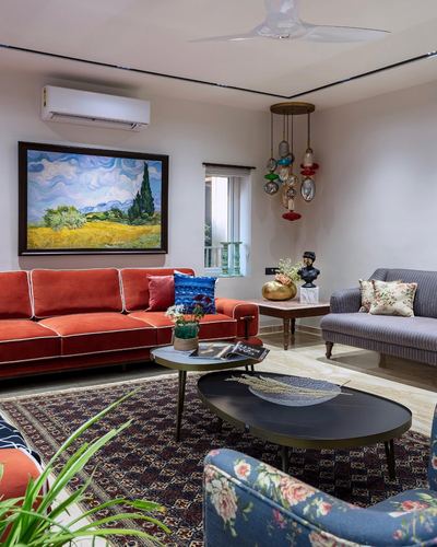 Living room with rust velvet sofa, floral chairs, patterned rug and glass pendant chandelier