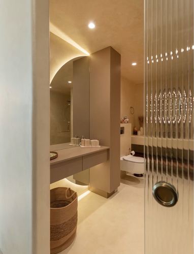 Warm-toned spa bathroom with arched niche, fluted cabinetry, and ribbed glass door