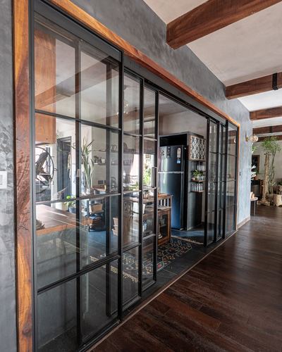 Corridor with dark wood floor leading to kitchen behind black steel-framed glass sliding doors