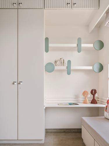 Off-white wardrobe and study nook with sage-green capsule shelves and cat-shaped door knobs.