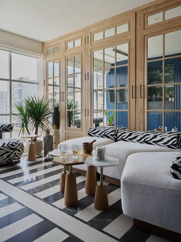 Living room with striped stone floor, mirrored wood doors, blue fluted panel, and zebra-print sofa cushions