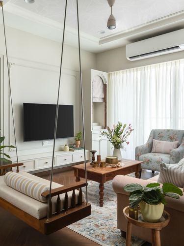 Living room with wooden hanging swing, floral armchair, coffee table, and arched storage niche