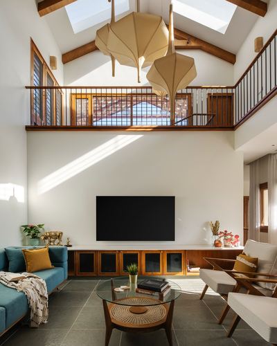 Double-height living room with skylight, mezzanine, teal sofa, and large sculptural pendant lights