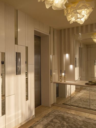 Entry foyer with fluted paneling, mirrored console, brass fixtures, and sculptural pendant light
