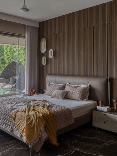 Bedroom with fluted wood wall, leather headboard, mustard throw, and view to garden with hanging chair
