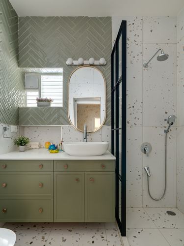 Green herringbone tile bathroom with oval mirror, vessel sink, and terrazzo shower area