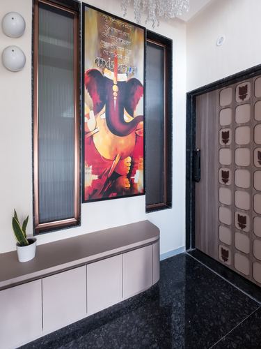 Foyer with Ganesha painting between reeded glass panels, black granite floor, carved wooden door
