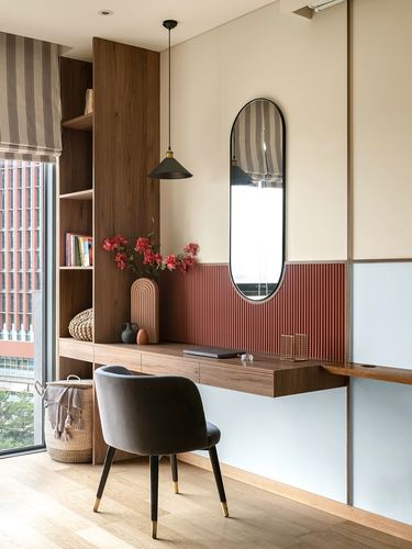 Wall-mounted wood desk with black chair, oval mirror over fluted terracotta panel, and pendant light