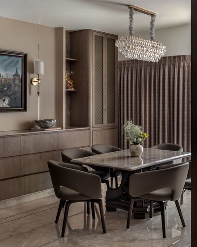 Dining room with marble table, leather chairs, wood cabinetry, and crystal chandelier