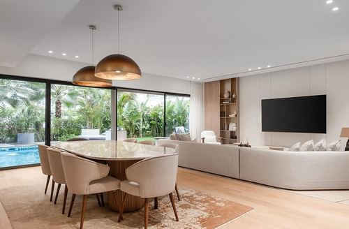 Open living-dining space with dome pendants over marble table and garden view through glass wall
