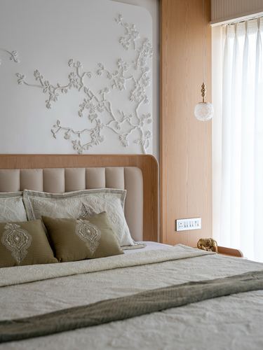 Bed with tufted headboard beneath sculpted plaster floral wall relief, pendant light beside window