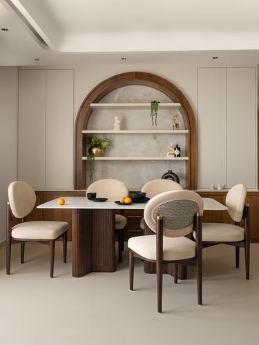 Dining area with arched wood-framed stone niche and cream oval-back chairs around fluted table