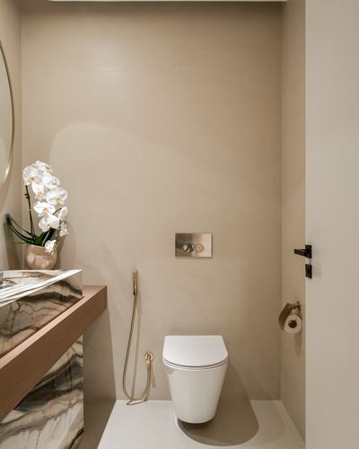 Powder room with plaster niche, wall-hung toilet, brass fittings, and veined stone vanity ledge