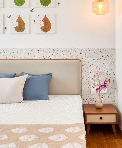 Bedroom corner with upholstered headboard, terrazzo wall panel, wooden nightstand and glass pendant light