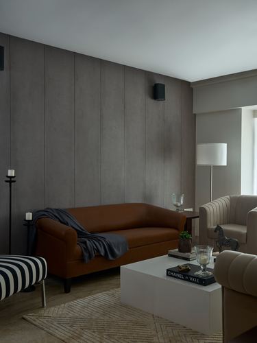 Living room with tan leather sofa against grey panelled wall and white coffee table