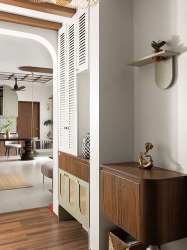 Foyer with louvered white cabinet, wooden console, and arched passage into living room