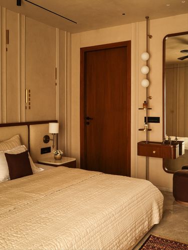 Warm-toned bedroom with panelled walls, wooden door, and brass vanity fixture beside mirror