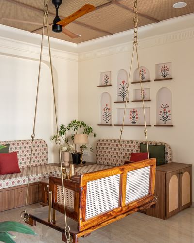Wooden cane swing hangs in a living room with arched niches holding block-print botanical art