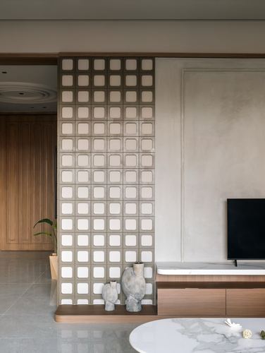 Living room with textured grid partition wall, ceramic vases, and TV console on marble-topped cabinet
