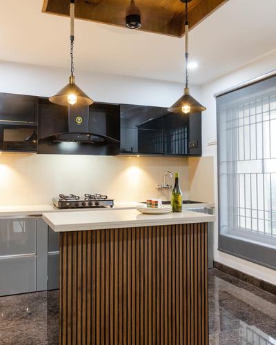 Modern kitchen island with fluted wood front, black cabinetry, and hanging pendant lights