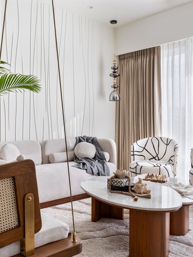 Living room corner with cane-backed swing, beige sofa, marble coffee table and fluted wall panel