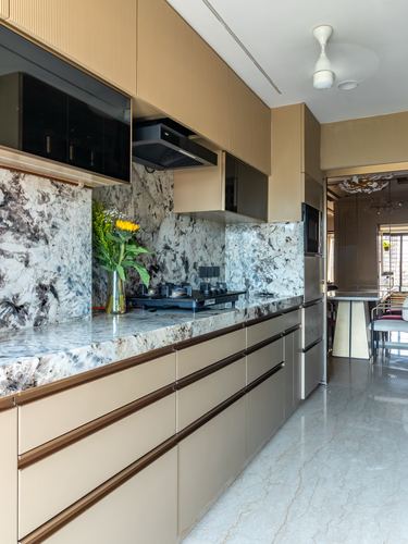 Beige fluted kitchen with veined stone backsplash, gas hob, and view through to dining area