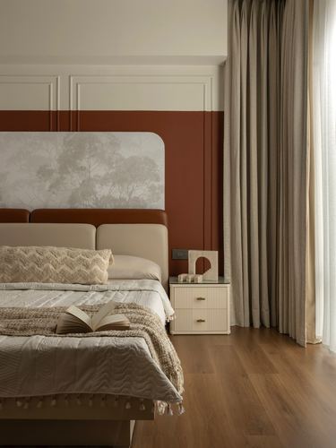 Bedroom with terracotta accent wall, upholstered headboard, and fluted nightstand beside sheer curtains
