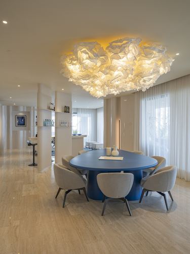 Dining area with blue oval table, grey chairs, and a cloud-shaped ceiling light fixture