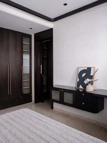 Dark wood wardrobe and floating console with framed graphic art in minimalist bedroom