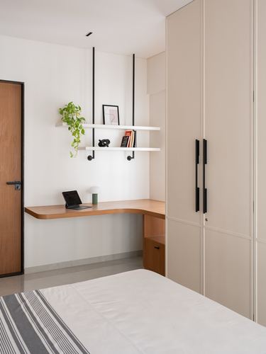 Corner study nook with hanging shelves, wooden desk and beige wardrobe in minimalist bedroom