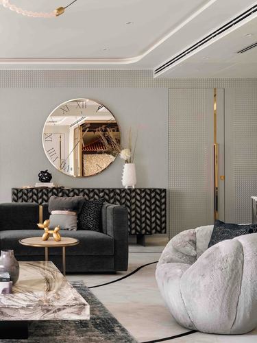Living room with dark velvet sofa, round mirror clock, marble coffee table and fur armchair