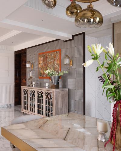 Foyer console with arched glass cabinet, artwork, and gold globe chandelier over marble table
