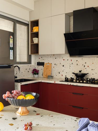 L-shaped kitchen with maroon cabinetry, terrazzo counters and backsplash, black chimney hood