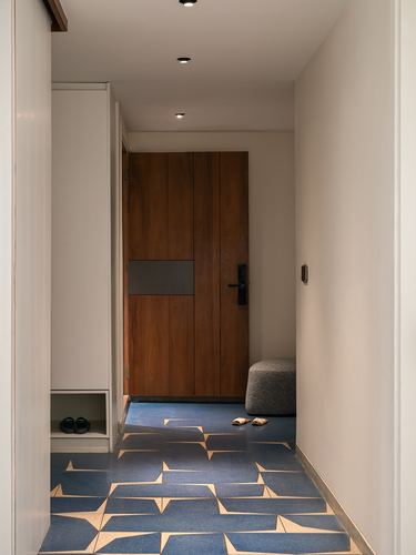 Narrow foyer with patterned blue terrazzo floor leading to a wooden entry door