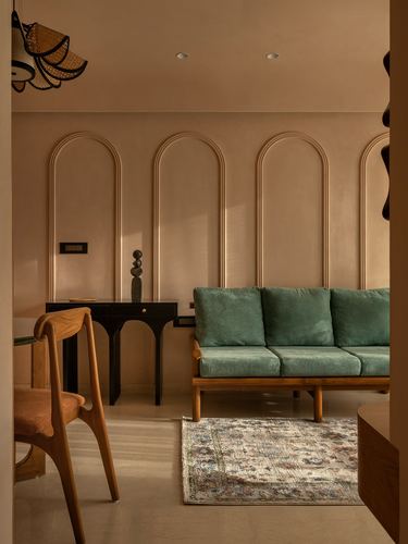 Living room with green velvet sofa against arched wall mouldings and black console table