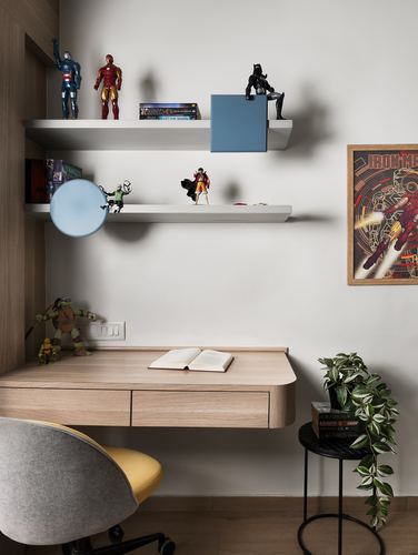 Wall-mounted desk with book, action figures on floating shelves, and a yellow chair below